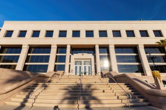 Modern courthouse with large stairs leading to the entrance, reflecting sunlight.