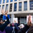 A crowd of protesters holding signs raises their arms in front of the U.S. Department of Education building. A crowd of protesters holding signs raises their arms in front of the U.S. Department of Education building.