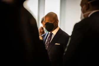 A Mayor Eric Adams speaking at a press conference, surrounded by other individuals.