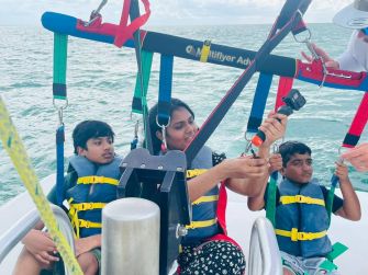 A woman and two children preparing for a parasailing excursion, with safety harnesses and life jackets on a boat in the ocean.