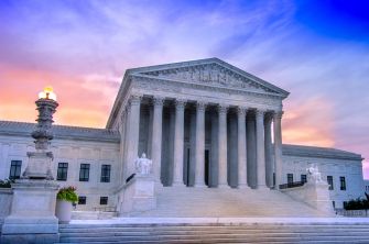 U.S. Supreme Court building at sunset, showcasing its architectural features.