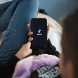 A person using a smartphone displaying the TikTok logo while relaxing on a bed. A person using a smartphone displaying the TikTok logo while relaxing on a bed.