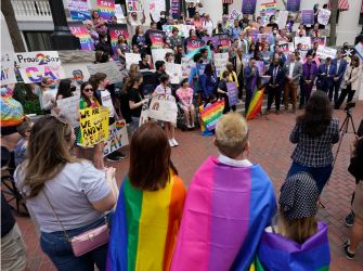 A group of protesters holding signs in support of LGBTQ+ rights, gathered outside in an organized demonstration against Florida's "Don't Say Gay" bill.