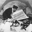A person inspecting ancient manuscripts and scrolls in a storage area. A person inspecting ancient manuscripts and scrolls in a storage area.
