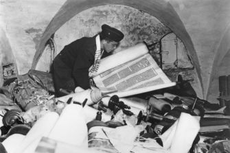 A person inspecting ancient manuscripts and scrolls in a storage area.