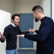 Two men appear to be in a heated argument in a doorway, gesturing expressively. Two men appear to be in a heated argument in a doorway, gesturing expressively.