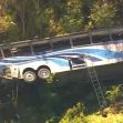 Aerial view of a charter bus that overturned at the edge of a ravine, with rescue personnel on the scene. Aerial view of a charter bus that overturned at the edge of a ravine, with rescue personnel on the scene.