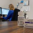 A bottle of mifepristone tablets is displayed in the foreground, with a person working at a computer in the background. A bottle of mifepristone tablets is displayed in the foreground, with a person working at a computer in the background.