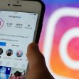 A person holds a smartphone displaying the Instagram app, with the Instagram logo blurred in the background. A person holds a smartphone displaying the Instagram app, with the Instagram logo blurred in the background.