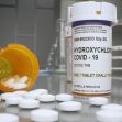A prescription bottle for hydroxychloroquine labeled for COVID-19 treatment, with pills spilled around it on a counter. A prescription bottle for hydroxychloroquine labeled for COVID-19 treatment, with pills spilled around it on a counter.