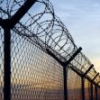 Barbed wire fencing at a prison against a sunset backdrop. Barbed wire fencing at a prison against a sunset backdrop.