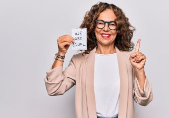 Smiling woman holding a sign that reads "WE ARE EQUAL."