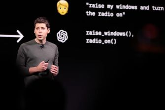 Sam Altman speaking during a presentation, with code and text displayed behind him.