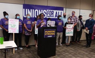 Group of advocates and legislators at a press conference supporting the Better Care Better Jobs Act, with signs advocating for fair wages and healthcare access.