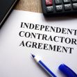 Document titled "Independent Contractor Agreement" with a pen and calculator on a desk. Document titled "Independent Contractor Agreement" with a pen and calculator on a desk.