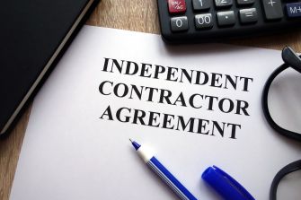 Document titled "Independent Contractor Agreement" with a pen and calculator on a desk.