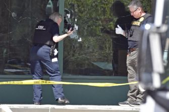 Investigation scene outside Old National Bank, showing law enforcement examining shattered windows following the mass shooting incident.