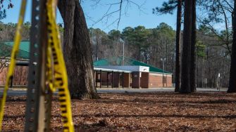 View of Richneck Elementary School with police tape and trees in the foreground.