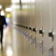 A corridor of school lockers with an out-of-focus figure walking in the background. A corridor of school lockers with an out-of-focus figure walking in the background.