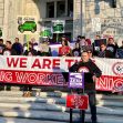 Demonstrators rallying for gig worker rights, holding signs and banners in front of a government building. Demonstrators rallying for gig worker rights, holding signs and banners in front of a government building.