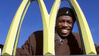 Retired MLB star Herb Washington smiling behind the McDonald's golden arches.