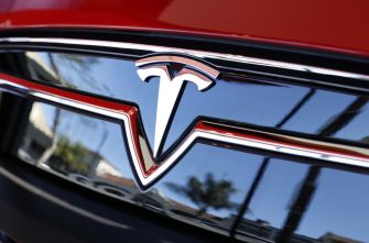 Tesla logo on the front of a red Tesla vehicle.