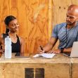A gym staff member assists a new member with paperwork at a fitness facility. A gym staff member assists a new member with paperwork at a fitness facility.