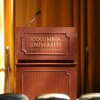 A podium with the Columbia University logo in a hall. A podium with the Columbia University logo in a hall.