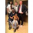 A group of people posing together, including a woman in a wheelchair holding a child. A group of people posing together, including a woman in a wheelchair holding a child.