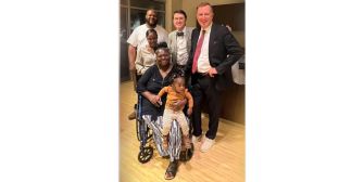 A group of people posing together, including a woman in a wheelchair holding a child.