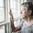 A senior woman looking thoughtfully out of a window. A senior woman looking thoughtfully out of a window.