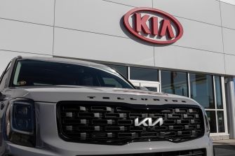 Kia logo displayed on dealership exterior with a Telluride vehicle in the foreground.