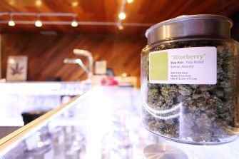 Jar of medical marijuana labeled "Blueberry" for pain relief, stress, and anxiety on display in a dispensary.