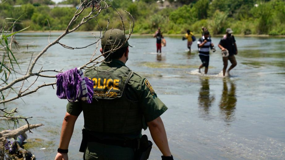 A Border Patrol agent watches as a group of migrants walk across the Rio Grande on their way to turn themselves in upon crossing the U.S.-Mexico border, Tuesday, June 15, 2021, in Del Rio, Texas. U.S. government data shows that 42% of all families encountered along the border in May hailed from places other than Mexico, El Salvador, Guatemala and Honduras — the traditional drivers of migratory trends. (AP Photo/Eric Gay)