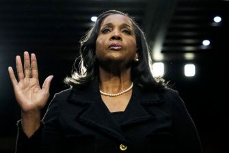 A woman taking an oath, standing in front of a panel, likely during a confirmation hearing or similar event.