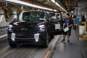 A Chevrolet vehicle on an assembly line with a worker inspecting it.