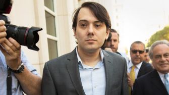 Martin Shkreli leaving a courthouse surrounded by people and media.