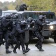 A SWAT team in tactical gear moving towards a vehicle during an operation. A SWAT team in tactical gear moving towards a vehicle during an operation.
