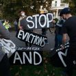 Protestors hold a "STOP EVICTIONS" sign in front of the house of Governor of Massachusetts, Charlie Baker, in Swampscott, Massachusetts, file photo, Oct. 14, 2020.