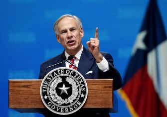 Texas Governor Greg Abbott speaking at a podium with the Texas state seal, addressing the veto of a bill to ban THC consumables.