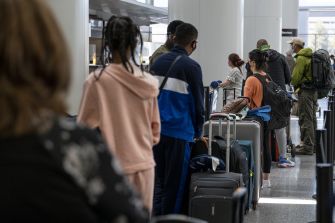 A queue of travelers at an airport security checkpoint, with individuals waiting to be processed.