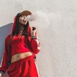 A person in a red outfit exhaling vapor against a white wall. A person in a red outfit exhaling vapor against a white wall.