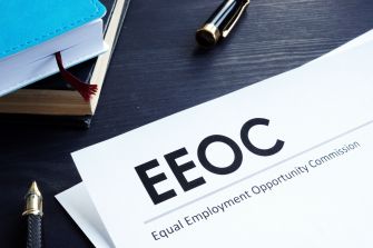 Document from the Equal Employment Opportunity Commission (EEOC) on discrimination and harassment in the construction industry, placed on a desk with a pen and notebooks.