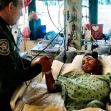 A police officer attending to a shooting survivor in a hospital bed. A police officer attending to a shooting survivor in a hospital bed.