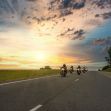 A group of motorcyclists riding on a highway during sunset with a cloudy sky. A group of motorcyclists riding on a highway during sunset with a cloudy sky.