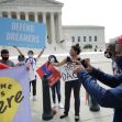 A group of individuals protesting outside a government building, holding signs that read "DEFEND DREAMERS" and "DEFEND DACA," advocating for the protection of DACA recipients. A group of individuals protesting outside a government building, holding signs that read "DEFEND DREAMERS" and "DEFEND DACA," advocating for the protection of DACA recipients.