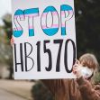 woman holding sign Stop Hb1570