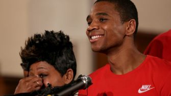 A smiling Davontae Sanford, with a woman partially visible in the background, speaks during a press conference about his wrongful incarceration and the $7.5 million settlement reached with the city of Detroit.