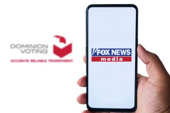 A person holding a smartphone displaying the Fox News logo alongside Dominion Voting Systems branding.
