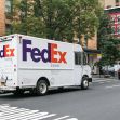 A FedEx delivery truck on a city street. A FedEx delivery truck on a city street.